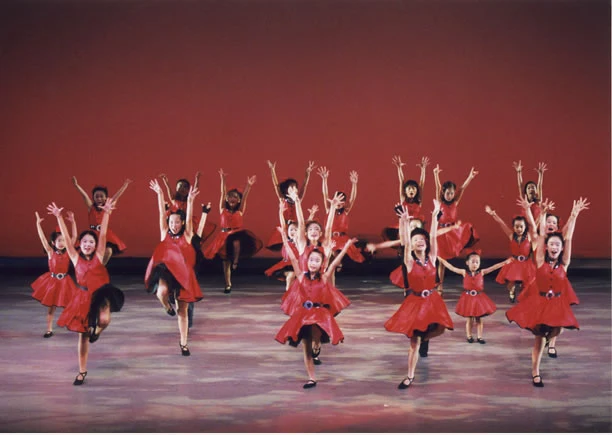 25周年記念公演で赤い衣装の出演者たちが踊る様子