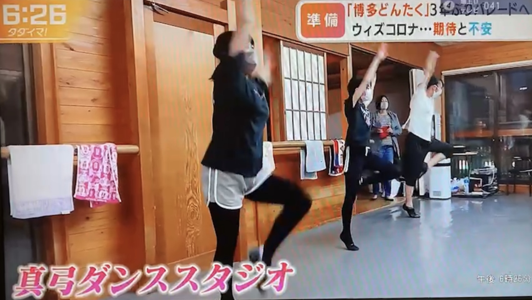 ダンススタジオ内で３名の生徒が両手を挙げて片膝を前に曲げて踊っているところ