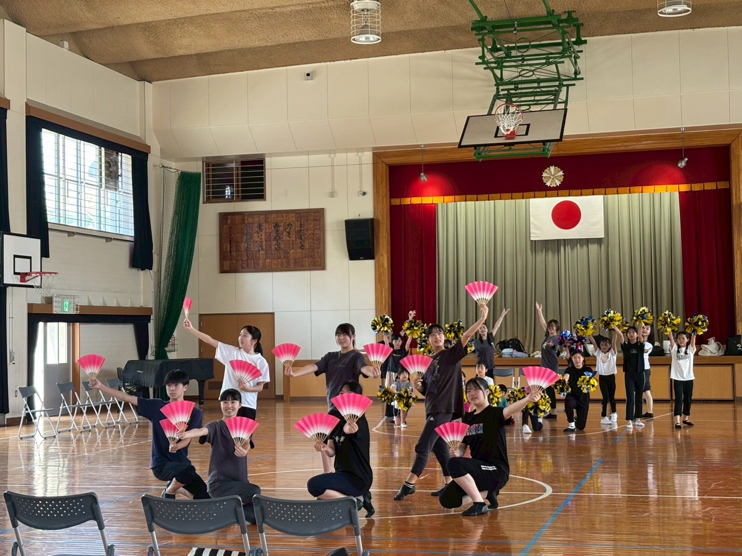 手前に扇を持った中高生、後ろに幼児から大人全員でポーズ