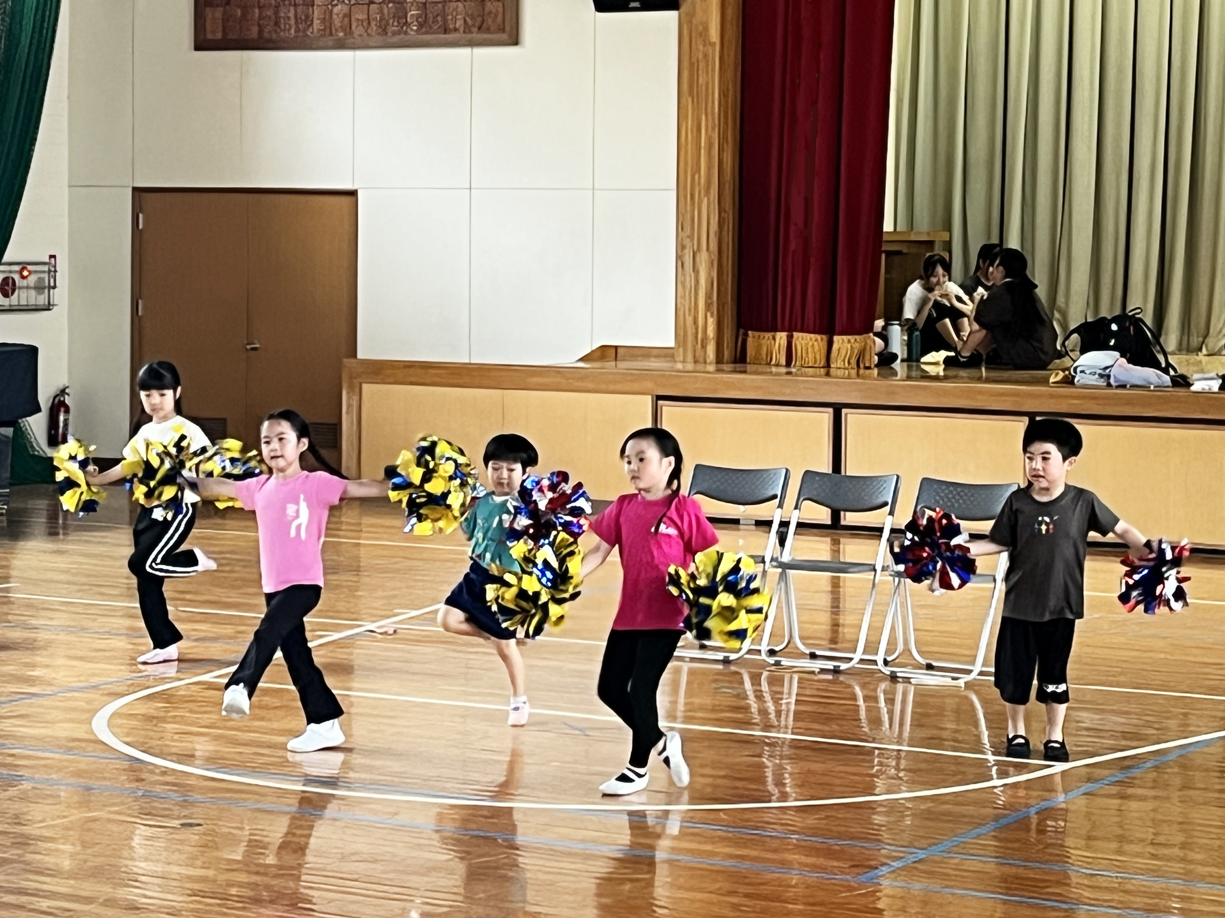 幼児から小学校低学年の子がポンポン持ってリズムをとっています