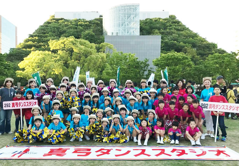 博多どんたく参加者がスタジオの横断幕とともに並ぶ集合写真