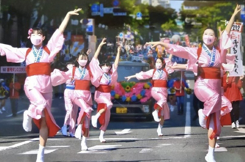 ピンクの着物の衣装を着た生徒が手を広げ綺麗にポーズをとっています