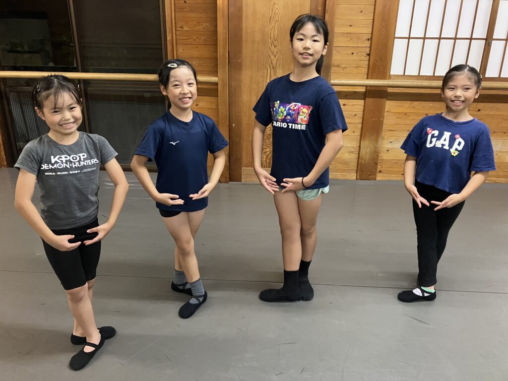 スタジオでバレエのポーズをとる4人の子どもたち