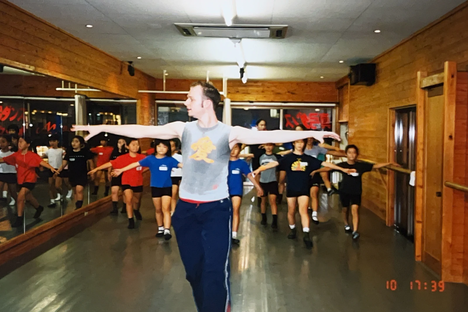 講師と参加者たちが腕を広げて踊るレッスン風景